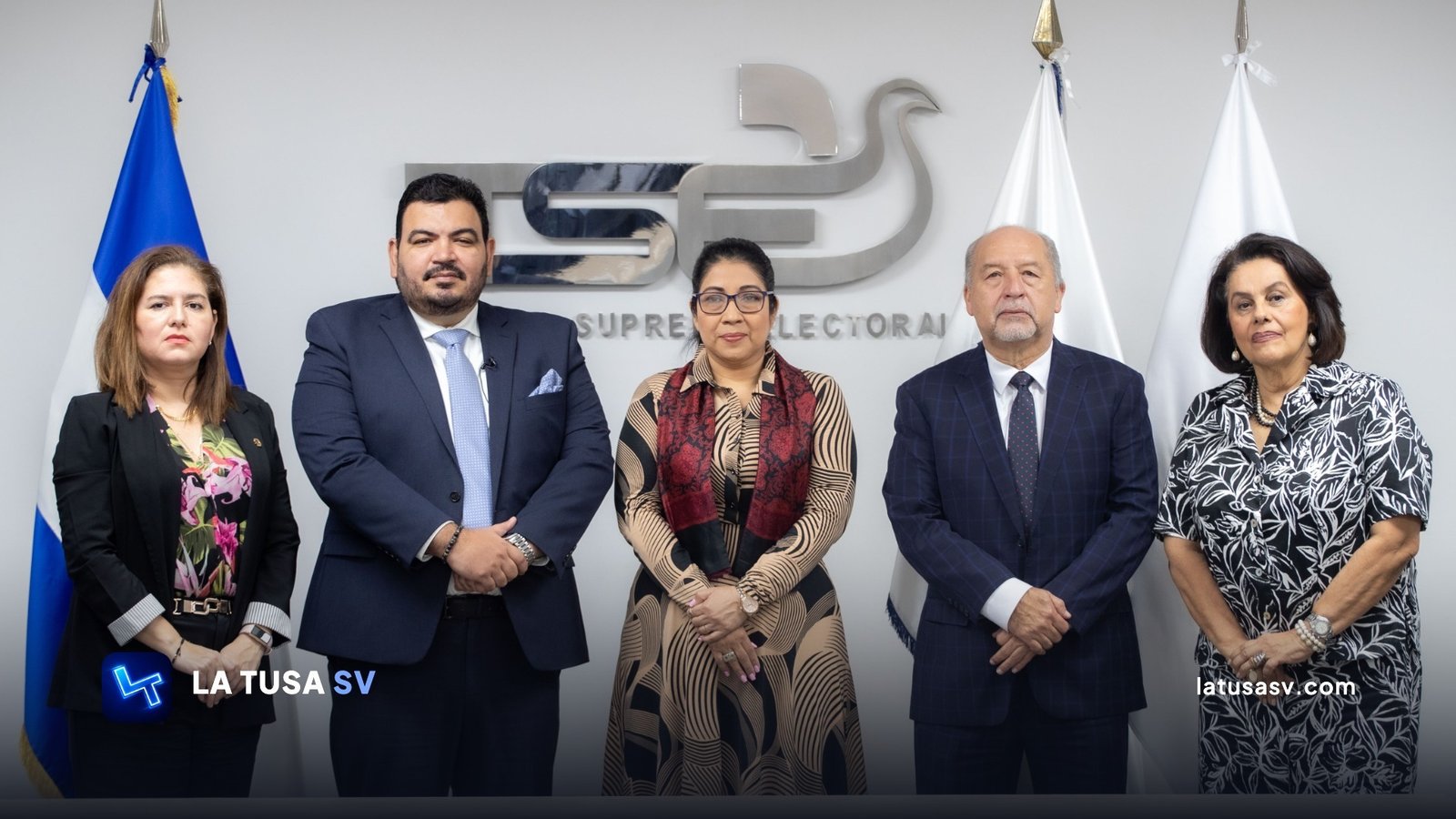 Los cinco magistrados del Tribunal Supremo Electoral de El Salvador posando frente al logotipo de la institución